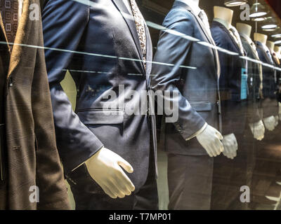 Gli uomini vestiti con camicie cravatte, pantaloni e giacche blu sul display manichini davanti a un sarto store, su una finestra. Si tratta di uno dei principali garme formale Foto Stock