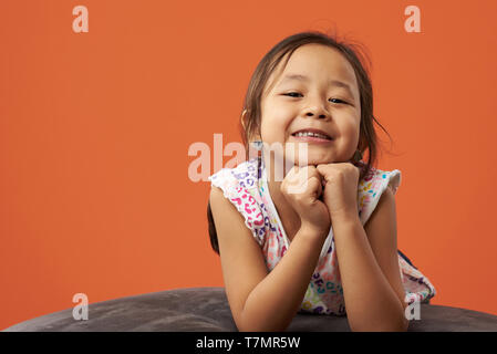 Asian kid che posano su un beanbag in un colore di sfondo. Filipina kid rilassante. Foto Stock