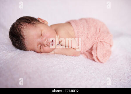 Un grazioso piccolo slepping Baby girl su soffice coltre di luce sullo sfondo Foto Stock