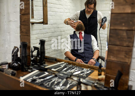 Elegante barbiere tagli brutali di un uomo con una folta barba. Foto Stock