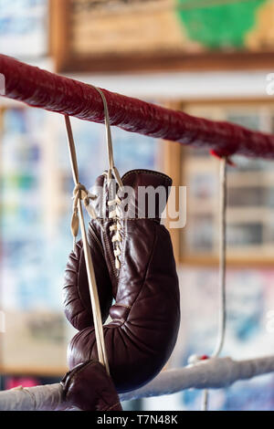 Un vecchio paio di guanti da boxe appesi a corde in una palestra pugilato ring Foto Stock