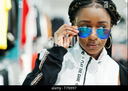 Afican donne americane in tute e occhiali da sole lo shopping al centro commerciale di abbigliamento sportivo. Lo sport store tema. Foto Stock