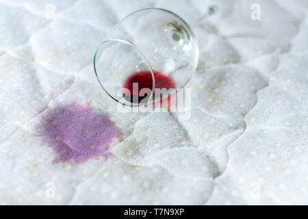 Eventuali fuoriuscite di vetro del vino sul letto. Caduta accidentale wineglass sul lenzuolo bianco. Sfortunato, spiacevole situazione. Macchia di bagnato. Foto Stock