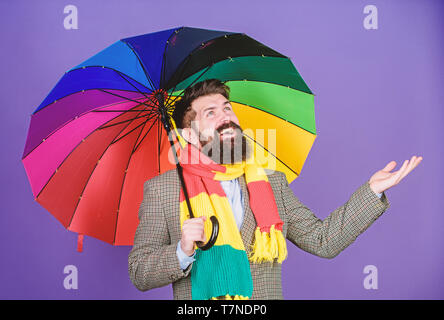 Guardando come la sua andando a pioggia. L'autismo. Autistico di rain man holding ombrello coloratissimo. Uomo Barbuto controllare se piove. Moda Uomo con accessori colorati. Egli non ha mai bisogno di preoccuparsi di giorni di pioggia. Foto Stock