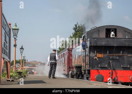 Vista posteriore di vintage UK locomotiva a vapore dalla piattaforma a Kidderminster SVR patrimonio stazione ferroviaria a Sunshine, macchinista in attesa di bandiera verde. Foto Stock