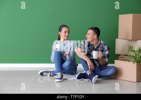 Coppia giovane di bere il caffè nei pressi di scatole in ambienti chiusi. Lo spostamento nella nuova casa Foto Stock