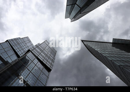 Grattacieli della città di Mosca sul burrascoso sfondo con cielo nuvoloso, vista dal basso. Città futuristica con drammatica sky, architettura moderna, concetto di urbanizzazione Foto Stock