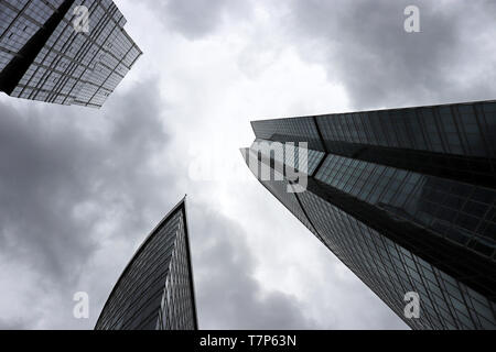 Grattacieli in stormy sfondo con cielo nuvoloso, vista dal basso. Città futuristica con drammatica sky, architettura moderna, concetto di urbanizzazione Foto Stock