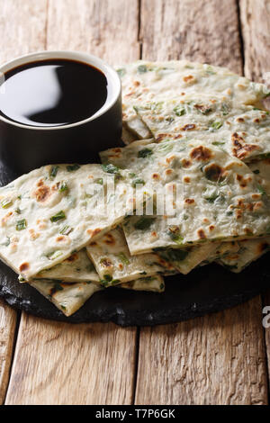 Flatbread cipolla fritti frittelle servite con salsa di close-up su una scheda sul piano verticale. Foto Stock