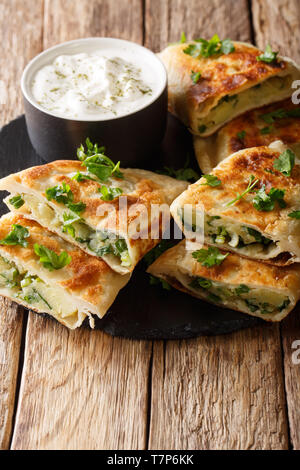 Bolani piatto il pane da Afghanistan, cotti al forno o fritti con un ripieno di verdure e servito con yogurt bianco closeup sul tavolo. In verticale Foto Stock