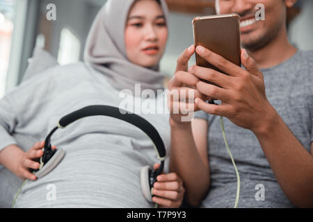 Donna incinta con cuffia sul suo ventre Foto Stock