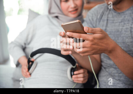 Donna incinta con cuffia sul suo ventre Foto Stock