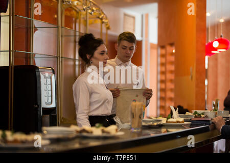 La Bielorussia, Vitebsk, 27 febbraio 2019. Il ristorante della città. Food festival cameriere con un vassoio.due baristi di un uomo e di una donna al contatore. I camerieri lavoro Foto Stock