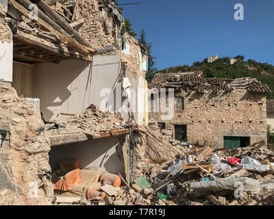 Un gravemente danneggiata casa rurale in Italia dopo un terremoto, la parete esterna è stata distrutta esponendo l'interno della casa, contro un cielo blu Foto Stock