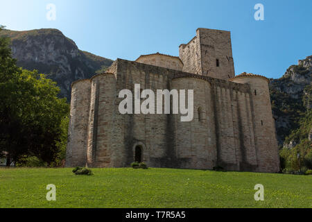 La splendida chiesa di San Vittore alle Chiuse con torri rotonde è un cattolico romano abbazia e chiesa nel comune di Genga, Marche, Italia contro un luminoso cielo blu Foto Stock