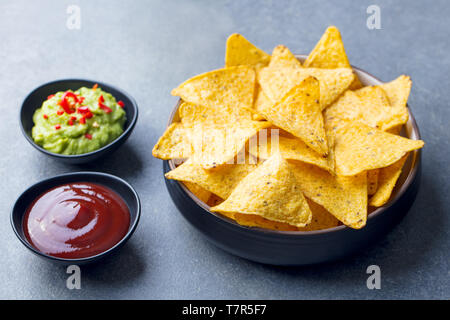 Nachos chips nella ciotola con salse, varietà dip. Grigio pietra dello sfondo. Close up. Foto Stock