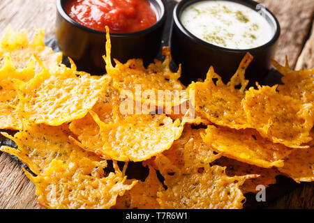 Naturale formaggio cheddar chip con erbe aromatiche con salse close-up su una scheda su una tavola orizzontale. Foto Stock