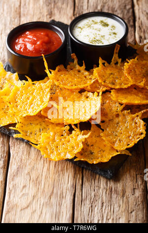 Fritti di formaggio cheddar chip con erbe aromatiche servita con salse close-up sul piano verticale. Foto Stock