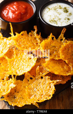 Il cheddar artigianale chip con erbe aromatiche servita con salse close-up sul piano verticale. Foto Stock