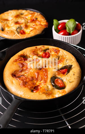 Concetto di alimenti freschi fatti in casa Focaccia organico nella padella padella di ferro su sfondo nero con spazio di copia Foto Stock