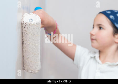 Bambina con rullo di vernice in mano. Bambini aiutando Casa concept Foto Stock