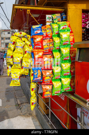Visualizzazione dei colorati pacchetti nitido appeso a testa in giù al di fuori di una banchina snack bar nel quartiere Mahipalpur, un sobborgo dall'aeroporto di Delhi, New Delhi, India Foto Stock