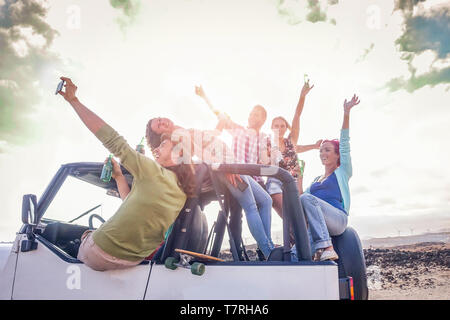 Gruppo di happy amici divertendosi sulla vettura convertibile in vacanza - i giovani a bere champagne e tenendo selfie durante il loro viaggio su strada Foto Stock