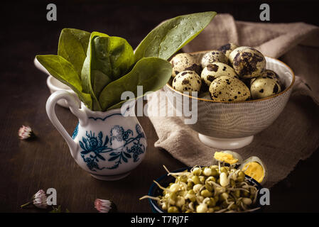 Foto orizzontale di poche foglie fresche di spinaci. Gli spinaci ha un bel colore verde e poche gocce di acqua sono su di essi. Gli spinaci sono in vaso in ceramica su woode scuro Foto Stock