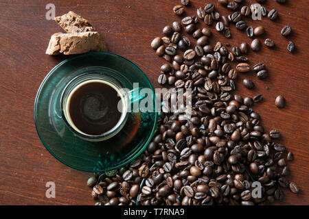 Tempo di caffè, una tazza di caffè con biscotti e i chicchi di caffè su sfondo scuro Foto Stock