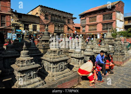 Famiglia locale in abiti colorati in appoggio su di una piazza con gli stupa sul sito di Swayambhunath tempio o Tempio delle Scimmie, Kathmandu, Nepal Foto Stock