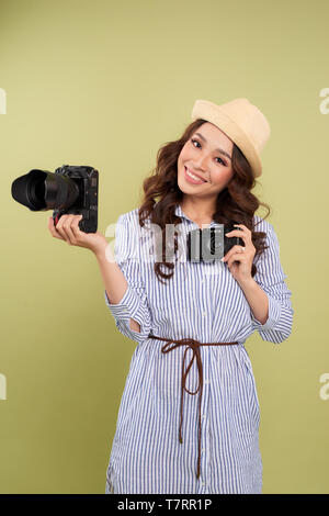 Giovane donna il confronto professionale e le fotocamere compatte su uno sfondo a tinta unita Foto Stock