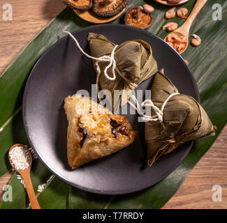 Zongzi, riso al vapore gnocchi di patate sul tavolo di legno foglie di bambù, cibo in dragon boat festival duanwu concetto, close up, copia spazio, vista dall'alto, laici piatta Foto Stock