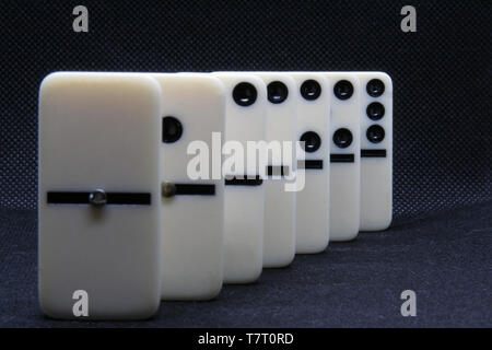 Il marmo bianco di domino su un colore nero dello sfondo. L'effetto domino su sfondo nero. Foto Stock