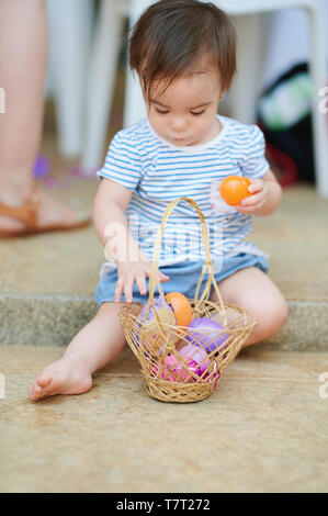 Il bambino gioca con le uova nel paniere durante le festività di Pasqua Caccia Foto Stock
