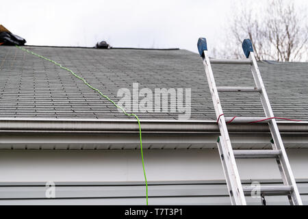 Primo piano frontale di casa durante il giorno su garage con colore grigio singolo casa di famiglia e di tegole e la scaletta durante la riparazione Foto Stock