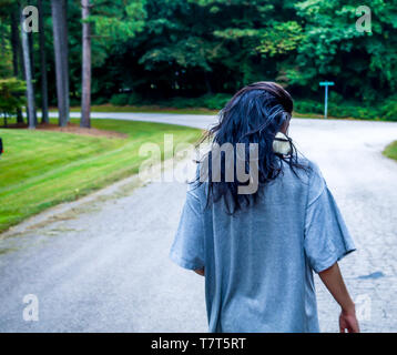 Una ragazza teen che cammina giù un quartiere con il suo animale domestico rat sulla spalla Foto Stock