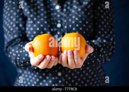 Arance nelle mani della ragazza. Una ragazza con una manicure trattiene le arance. Close up Foto Stock