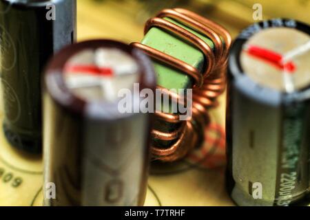 La fotografia macro della bobina elettromagnetica, condensatori e altri componenti elettronici in una scheda elettronica Foto Stock