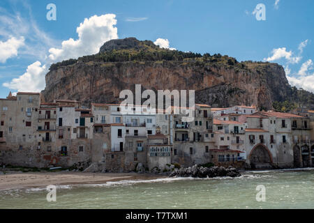 Storico case sulla spiaggia con La Rocca dietro nella pittoresca città di Cefalù, Sicilia. Foto Stock