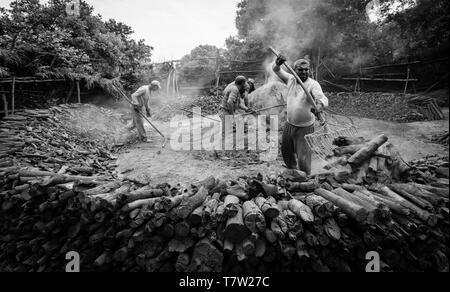 Lavoratori che fanno del carbone di legna per utilizzo in un barbeque Foto Stock