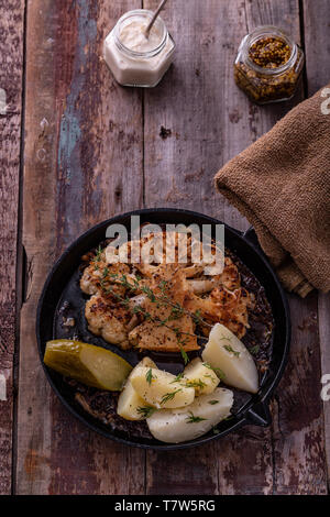 Vegetariano cavolfiore arrosto bistecca con patate su una padella Foto Stock