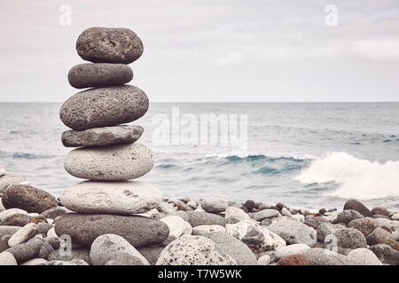 Nei toni del colore dell'immagine di una pila di pietra su una spiaggia, equilibrio e armonia concetto, il fuoco selettivo. Foto Stock