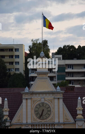 Brasov, Romania - Agosto 2017: Bandiera della Romania e orologio sulla Città di Brasov facciata Hall (Primaria Municipiului Brasov). Transilvania, Romania. Foto Stock