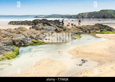 I turisti ad esplorare le rocce esposte a bassa marea su Towan Beach in Newquay in Cornovaglia. Foto Stock