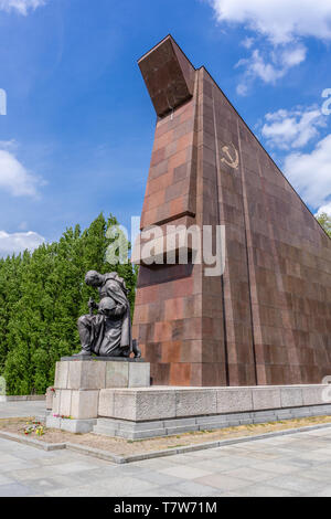 Statua di un soldato sovietico inginocchiato di fronte a una bandiera sovietica stilizzata costruita in granito rosso al Memoriale di guerra sovietico di Berlino Treptow, Berlino Foto Stock