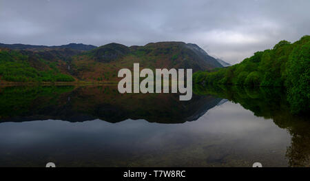 Llyn Dinas, Galles - 1 Maggio 2019: Ancora acque e riflessioni sulla Llyn Dinas nel Parco Nazionale di Snowdonia, Galles Foto Stock