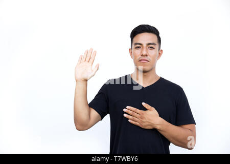 Grave ispanica latina ragazzo giura o promette di fare qualcosa, mantiene la mano sul petto, gesti con Palm. Isolato su sfondo bianco. Foto Stock