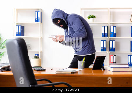 Ladro maschio in passamontagna in ufficio Foto Stock