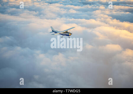 Piccolo motore unico aereo in uno splendido tramonto cielo attraverso il mare di nubi Foto Stock