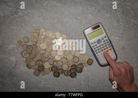 Un sacco di monete in euro con una calcolatrice. sfondo di monete. Tipica immagine di risparmio delle famiglie. Foto Stock